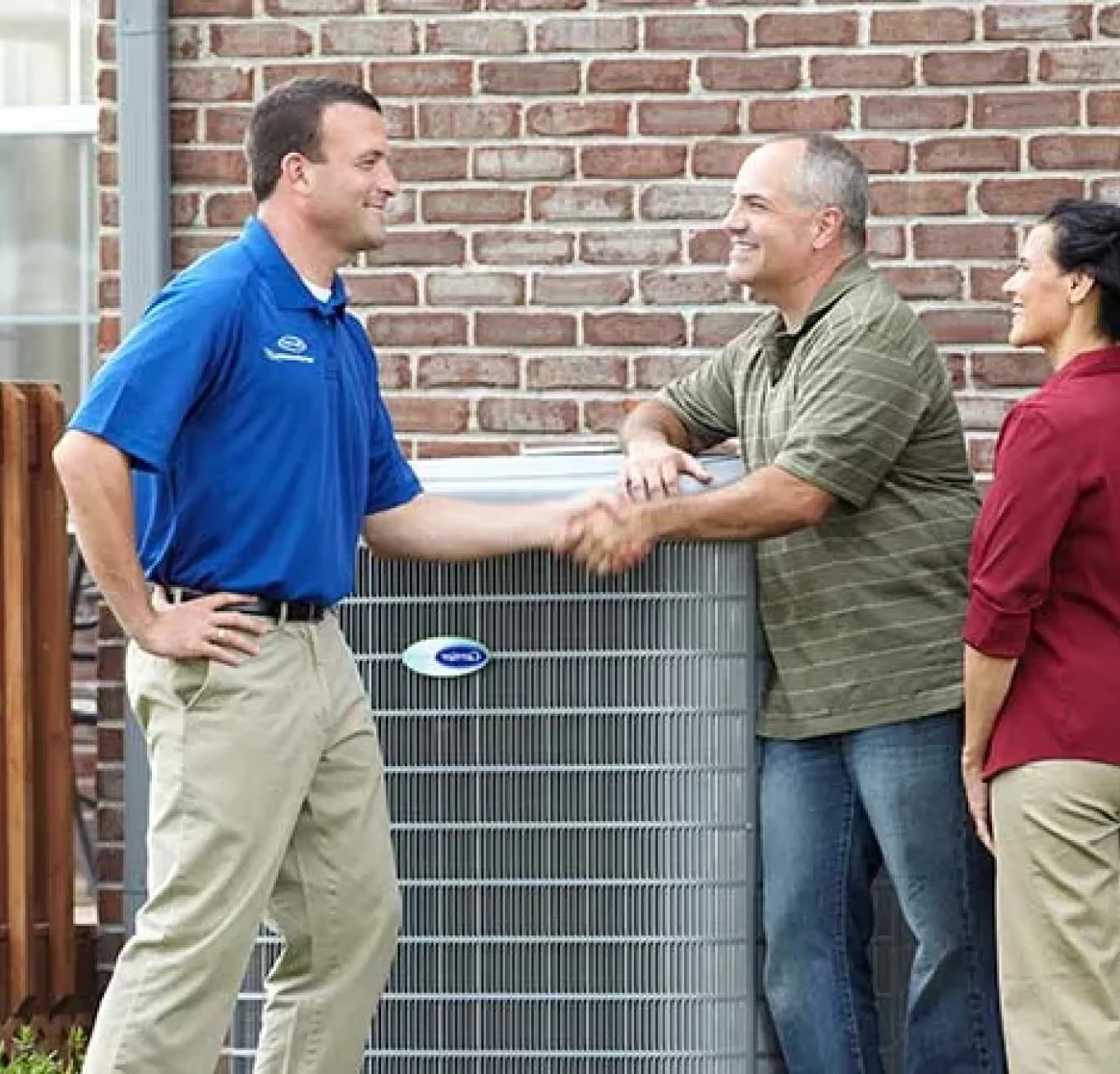 Air Experts technician shaking hands with homeowners next to their HVAC system